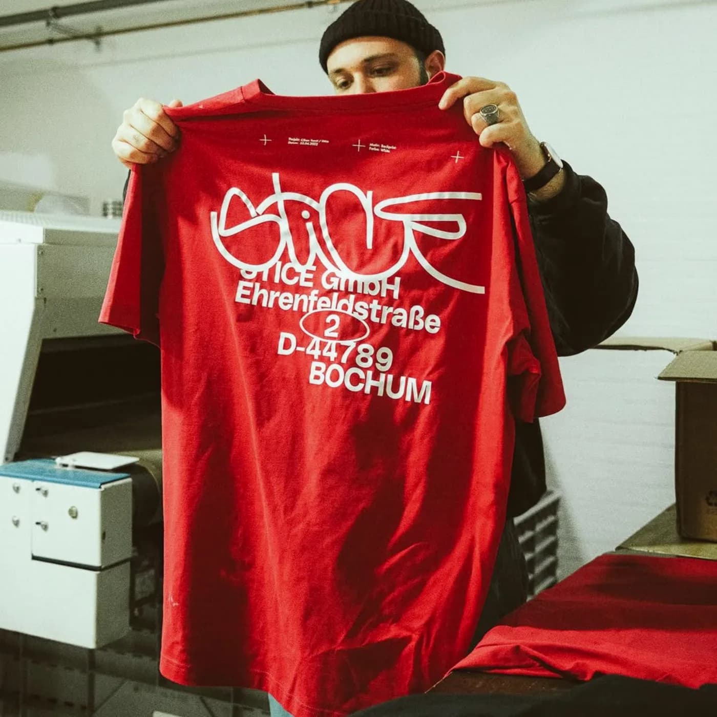 Red graphic T-shirt held up in a merchandise production studio