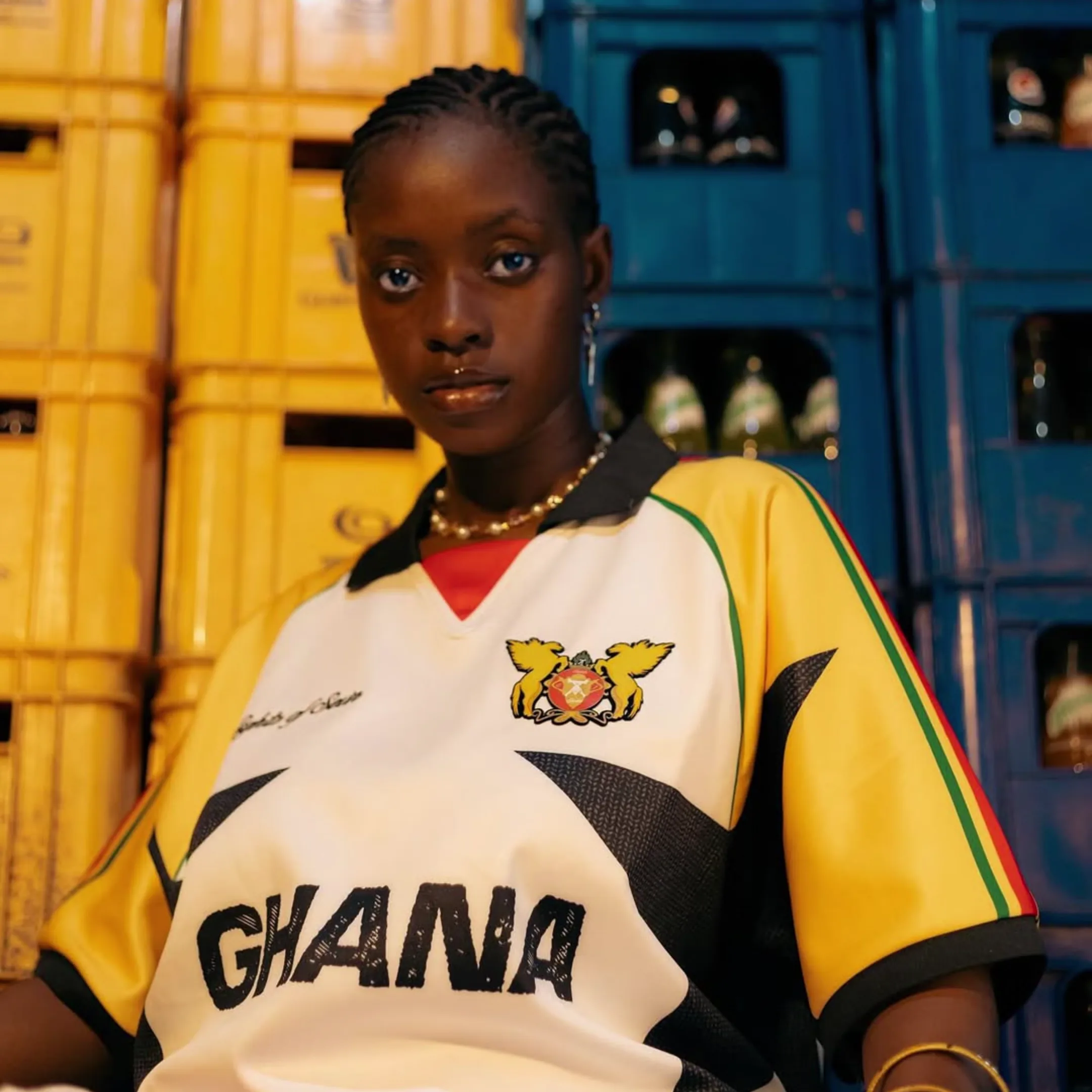 Model wearing a vivid yellow, white and black graphic football-style shirt